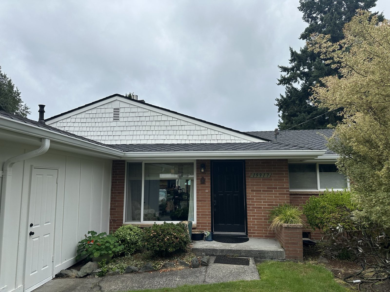Brick-and-white rambler with a completed dark composition roof