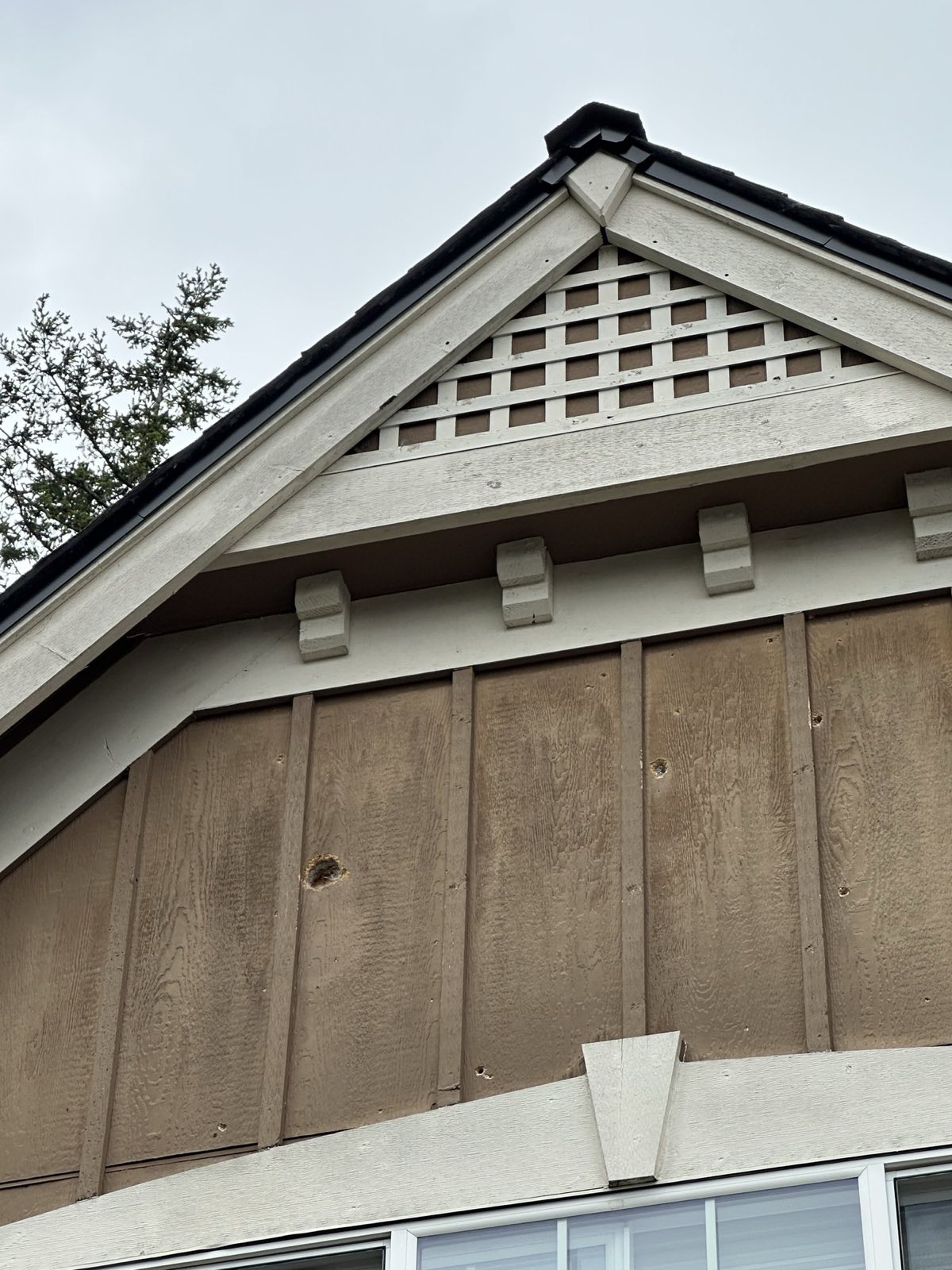Gable peak with lattice vent, corbels, and board-and-batten siding detail